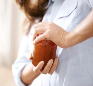 woman trying to open a jar in the kitchen